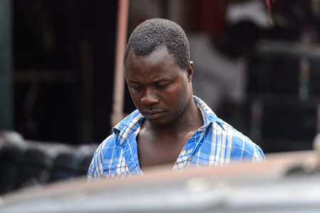 KUMASI, GHANA - Jan 16, 2017: Unidentified Ghanaian man in plaid shirt looks down. People of Ghana suffer of poverty due to the bad economyのeditorial素材