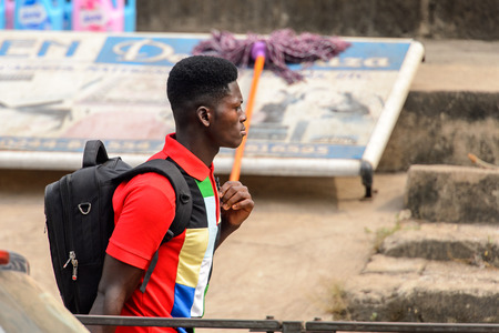 KUMASI, GHANA - Jan 16, 2017: Unidentified Ghanaian young man walks with backpack . People of Ghana suffer of poverty due to the bad economyのeditorial素材