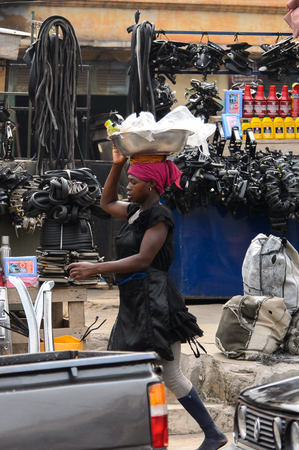 KUMASI, GHANA - Jan 16, 2017: Unidentified Ghanaian woman carries a basin on her head. People of Ghana suffer of poverty due to the bad economyのeditorial素材