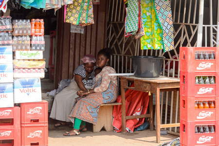 CENTRAL REGION, GHANA - Jan 17, 2017: Unidentified Ghanaian women sit on a wooden bench in local village. People of Ghana suffer of poverty due to the bad economyのeditorial素材