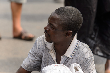 KUMASI, GHANA - Jan 16, 2017: Unidentified Ghanaian man squats on the street. People of Ghana suffer of poverty due to the bad economyのeditorial素材