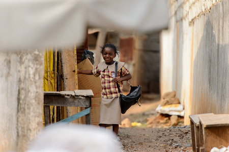 KUMASI, GHANA - Jan 16, 2017: Unidentified Ghanaian girl with bag and in plaid shirt looks ahead. Children of Ghana suffer of poverty due to the bad economyのeditorial素材
