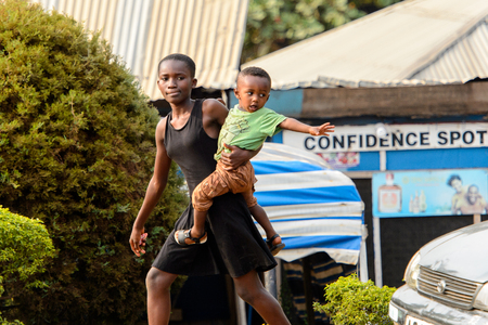 KUMASI, GHANA - Jan 16, 2017: Unidentified Ghanaian woman carries her baby. People of Ghana suffer of poverty due to the bad economyのeditorial素材