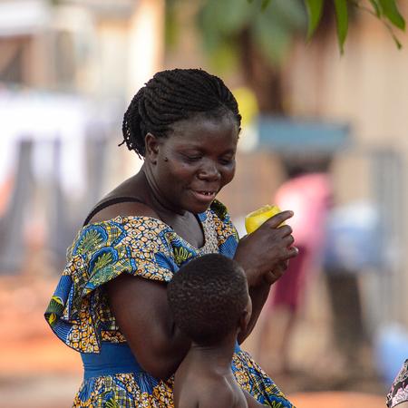 KUMASI, GHANA - Jan 16, 2017: Unidentified Ghanaian woman in colored dress with braids talks to her son . People of Ghana suffer of poverty due to the bad economyのeditorial素材