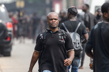 KUMASI, GHANA - Jan 16, 2017: Unidentified Ghanaian man in black shirt with backpack walks on the street. People of Ghana suffer of poverty due to the bad economyのeditorial素材