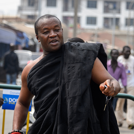 KUMASI, GHANA - Jan 16, 2017: Unidentified Ghanaian man in black clothes walks on the street. People of Ghana suffer of poverty due to the bad economyのeditorial素材