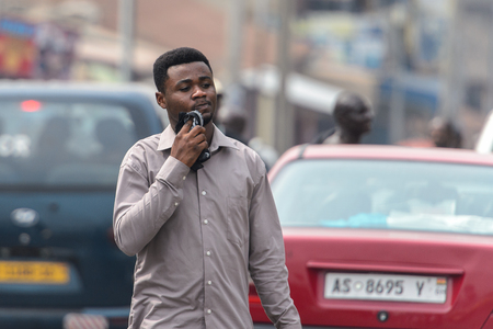 KUMASI, GHANA - Jan 16, 2017: Unidentified Ghanaian man in grey shirt walks on the street. People of Ghana suffer of poverty due to the bad economyのeditorial素材