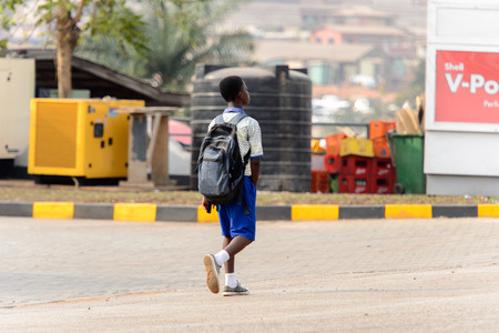 KUMASI, GHANA - Jan 16, 2017: Unidentified Ghanaian pupil in uniform walks along the road. Children of Ghana suffer of poverty due to the bad economyのeditorial素材