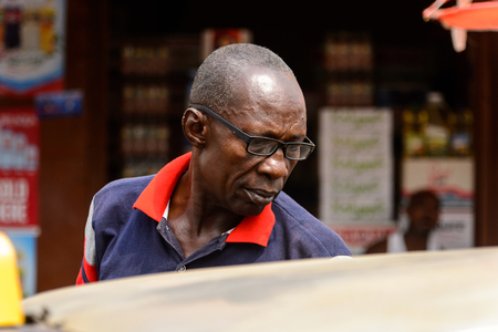 KUMASI, GHANA - Jan 16, 2017: Unidentified Ghanaian man in colored shirt and glasses looks down. People of Ghana suffer of poverty due to the bad economyのeditorial素材
