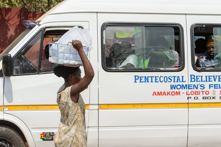 CENTRAL REGION, GHANA - Jan 17, 2017: Unidentified Ghanaian woman carries a basket on her head in local village. People of Ghana suffer of poverty due to the bad economyのeditorial素材