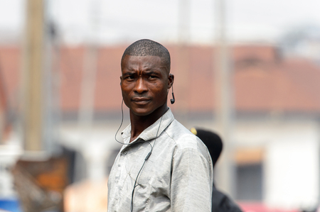 KUMASI, GHANA - Jan 16, 2017: Unidentified Ghanaian man in grey shirt listens to music. People of Ghana suffer of poverty due to the bad economyのeditorial素材