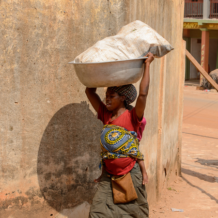 CENTRAL REGION, GHANA - Jan 17, 2017: Unidentified Ghanaian woman carries a basin on her head in local village. People of Ghana suffer of poverty due to the bad economyのeditorial素材