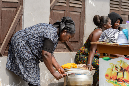 KUMASI, GHANA - Jan 16, 2017: Unidentified Ghanaian woman bends down to open the pan. People of Ghana suffer of poverty due to the bad economyのeditorial素材