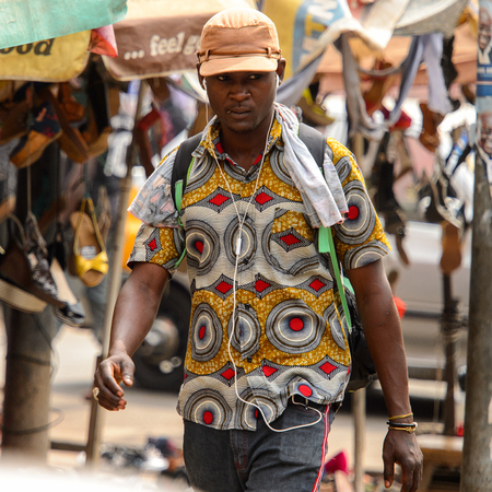 KUMASI, GHANA - Jan 16, 2017: Unidentified Ghanaian man in colored shirt listens to music. People of Ghana suffer of poverty due to the bad economyのeditorial素材