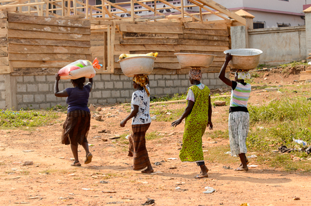 CENTRAL REGION, GHANA - Jan 17, 2017: Unidentified Ghanaian women walk with basins on their heads in local village. People of Ghana suffer of poverty due to the bad economyのeditorial素材