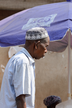 CENTRAL REGION, GHANA - Jan 17, 2017: Unidentified Ghanaian man in white shirt and skullcap looks down in local village. People of Ghana suffer of poverty due to the bad economyのeditorial素材