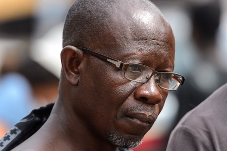 KUMASI, GHANA - Jan 16, 2017: Unidentified Ghanaian man in glasses with beard looks ahead. People of Ghana suffer of poverty due to the bad economyのeditorial素材