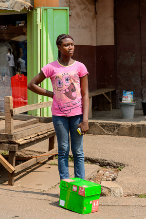 CENTRAL REGION, GHANA - Jan 17, 2017: Unidentified Ghanaian woman in pink shirt with braids stands in local village. People of Ghana suffer of poverty due to the bad economyのeditorial素材