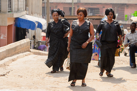 CENTRAL REGION, GHANA - Jan 17, 2017: Unidentified Ghanaian women in black dresses walk along the street in local village. People of Ghana suffer of poverty due to the bad economyのeditorial素材