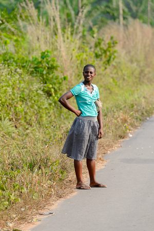 CENTRAL REGION, GHANA - Jan 17, 2017: Unidentified Ghanaian woman stands beside the road in local village. People of Ghana suffer of poverty due to the bad economyのeditorial素材