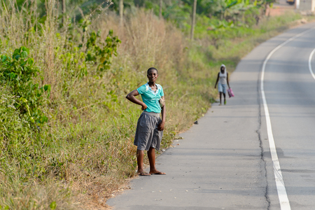 CENTRAL REGION, GHANA - Jan 17, 2017: Unidentified Ghanaian woman stands beside the road in local village. People of Ghana suffer of poverty due to the bad economyのeditorial素材