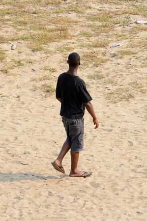 ELMINA, GHANA -JAN 18, 2017: Unidentified  Ghanaian man from behind walks on the coast of Elmina. People of Ghana suffer of poverty due to the bad economyのeditorial素材