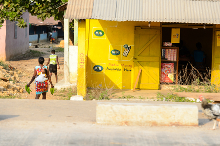 CENTRAL REGION, GHANA - Jan 17, 2017: Unidentified Ghanaian woman carries  a baby on her back in local village. People of Ghana suffer of poverty due to the bad economyのeditorial素材