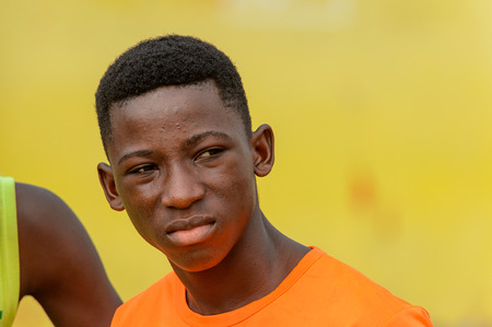 ELMINA, GHANA -JAN 18, 2017: Unidentified  Ghanaian boy in orange shirt looks away in Elmina. People...