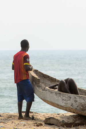 ELMINA, GHANA -JAN 18, 2017: Unidentified  Ghanaian men near the broken boat in Elmina coast. People of Ghana suffer of poverty due to the bad economyのeditorial素材