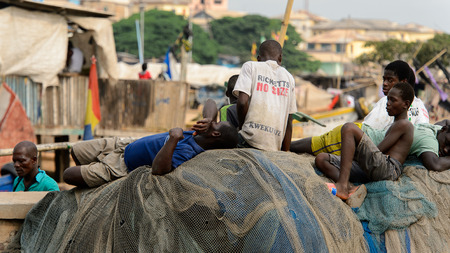 ELMINA, GHANA -JAN 18, 2017: Unidentified  Ghanaian men rest on the fising net in Elmina port. People of Ghana suffer of poverty due to the bad economyのeditorial素材