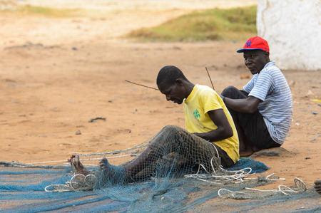 ELMINA, GHANA -JAN 18, 2017: Unidentified  Ghanaian men weave a fishing net on the coast of Elmina. People of Ghana suffer of poverty due to the bad economyのeditorial素材