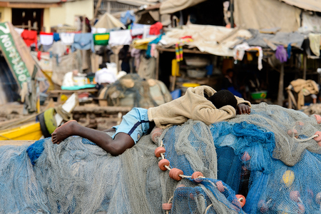 ELMINA, GHANA -JAN 18, 2017: Unidentified  Ghanaian man rests on the fising net in Elmina port. People of Ghana suffer of poverty due to the bad economyのeditorial素材