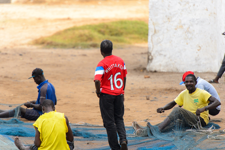 ELMINA, GHANA -JAN 18, 2017: Unidentified  Ghanaian men weave a fishing net on the coast of Elmina. People of Ghana suffer of poverty due to the bad economyのeditorial素材