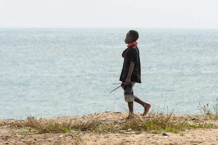 ELMINA, GHANA -JAN 18, 2017: Unidentified  Ghanaian boy walks on the coast of Elmina. Children of Ghana suffer of poverty due to the bad economyのeditorial素材