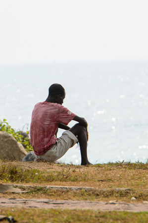 ELMINA, GHANA -JAN 18, 2017: Unidentified  Ghanaian man sits from behind on the coast of Elmina. People of Ghana suffer of poverty due to the bad economyのeditorial素材