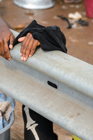 ELMINA, GHANA -JAN 18, 2017: Unidentified  Ghanaian woman hides behind the fence in Elmina market. People of Ghana suffer of poverty due to the bad economyのeditorial素材