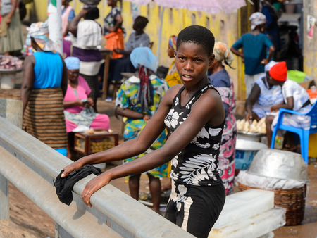 ELMINA, GHANA -JAN 18, 2017: Unidentified  Ghanaian woman stands near the fence in Elmina market....