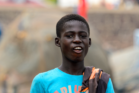 ELMINA, GHANA -JAN 18, 2017: Unidentified  Ghanaian boy in blue shirt shows his teeth in Elmina port. People of Ghana suffer of poverty due to the bad economyのeditorial素材