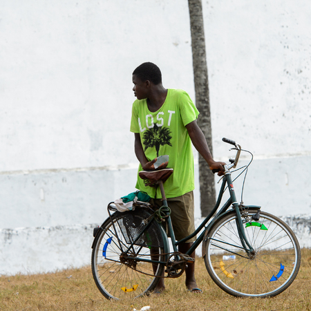 ELMINA, GHANA -JAN 18, 2017: Unidentified  Ghanaian man pulls his bicycle on the coast of Elmina. People of Ghana suffer of poverty due to the bad economyのeditorial素材