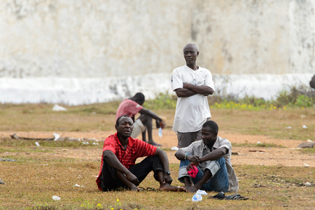 ELMINA, GHANA -JAN 18, 2017: Unidentified  Ghanaian men sit on the ground on the coast of Elmina. People of Ghana suffer of poverty due to the bad economyのeditorial素材