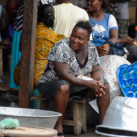 ELMINA, GHANA -JAN 18, 2017: Unidentified  Ghanaian woman sits on wooden chair in Elmina port. People of Ghana suffer of poverty due to the bad economyのeditorial素材