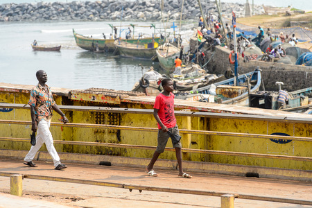 ELMINA, GHANA -JAN 18, 2017: Unidentified  Ghanaian people walk along the shore of Elmina port. People of Ghana suffer of poverty due to the bad economyのeditorial素材