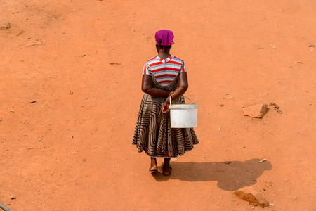 ELMINA, GHANA -JAN 18, 2017: Unidentified  Ghanaian woman from behind walks on the street in Elmina. People of Ghana suffer of poverty due to the bad economyのeditorial素材