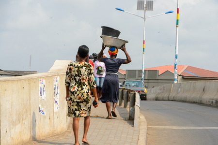 ELMINA, GHANA -JAN 18, 2017: Unidentified  Ghanaian woman walks along the road in Elmina port. People of Ghana suffer of poverty due to the bad economyのeditorial素材