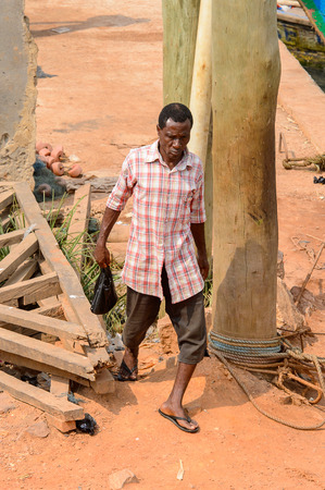 ELMINA, GHANA -JAN 18, 2017: Unidentified  Ghanaian man in plaid shirt walks in Elmina . People of Ghana suffer of poverty due to the bad economy.のeditorial素材