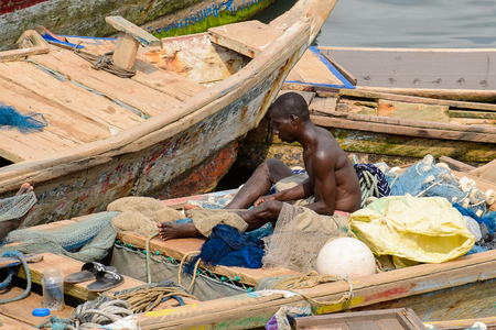 ELMINA, GHANA -JAN 18, 2017: Unidentified  Ghanaian man works on the boat in Elmina port. People of Ghana suffer of poverty due to the bad economyのeditorial素材
