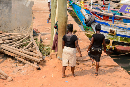 ELMINA, GHANA -JAN 18, 2017: Unidentified  Ghanaian women walk along the Elmina port. People of Ghana suffer of poverty due to the bad economyのeditorial素材