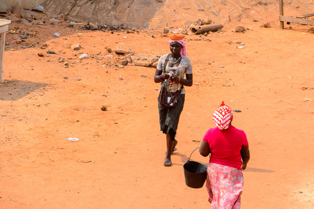 ELMINA, GHANA -JAN 18, 2017: Unidentified  Ghanaian woman carries a bucket from behind on the coast of Elmina. People of Ghana suffer of poverty due to the bad economyのeditorial素材