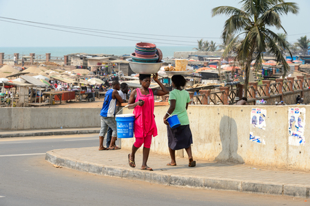 ELMINA, GHANA -JAN 18, 2017: Unidentified  Ghanaian people walk along the shore of Elmina port. People of Ghana suffer of poverty due to the bad economyのeditorial素材