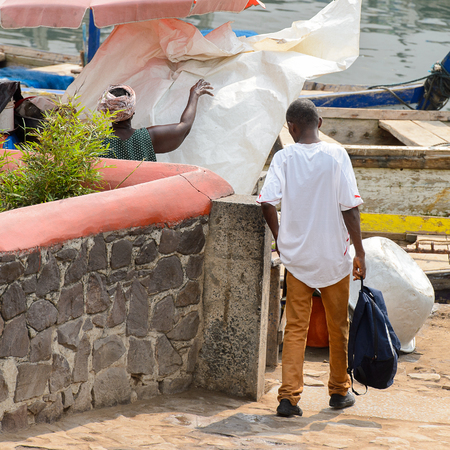 ELMINA, GHANA -JAN 18, 2017: Unidentified  Ghanaian man with backpack looks down in Elmina port. People of Ghana suffer of poverty due to the bad economyのeditorial素材